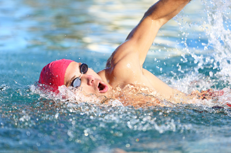 Man swimmer swimming crawl in blue water